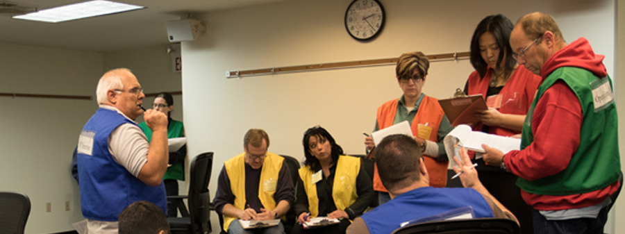 Numerous people dressed in colored vests are listing to instruction during an earthquake course at CSTI